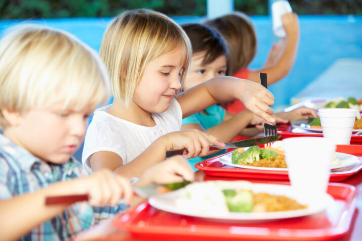 elementary pupils enjoying healthy lunch in cafeteria